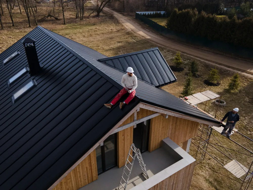 Contractor working on a dark standing seam metal roof